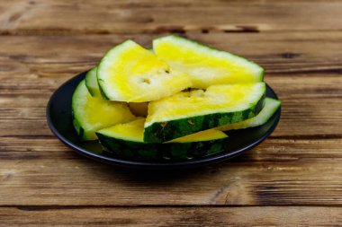 Tahta bir masada, taze, olgun, sarı bir karpuz.