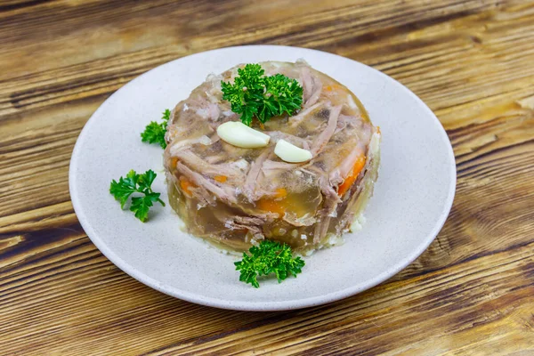 Meat aspic in a plate on a wooden table. Traditional russian dish