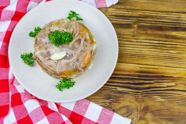 Meat aspic in a plate on a wooden table. Top view. Traditional russian dish