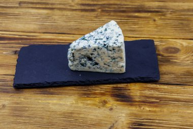 Ahşap masada siyah tahta servis edilen küflü mavi peynir.