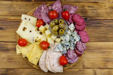 Zeytinli antipasti tabağı, kiraz domatesleri, ahşap bir masada İtalyan salamı ve peyniri çeşitleri. Üst görünüm