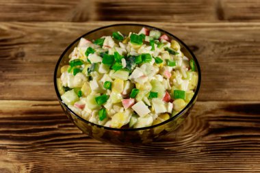 Yengeç çubuklu salata, mısır, salatalık, yumurta, pirinç ve mayonez ahşap masada.