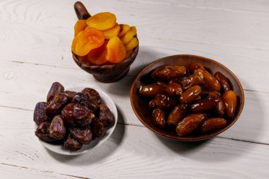 Kurumuş kayısılar ve beyaz ahşap masada meyveler.