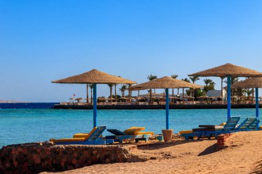 Tropik plajlarda güneş şemsiyeleri ve şezlonglar. Dinlenme, rahatlama, tatil, tatil