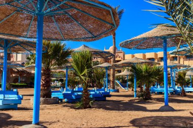 Tropik plajlarda güneş şemsiyeleri ve şezlonglar. Dinlenme, rahatlama, tatil, tatil