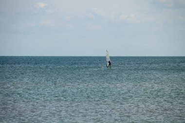 Rüzgar sörfü. Sakin denizde ya da okyanusta egzersiz yapan bir sörfçü. Yaz tatili boyunca eğlence amaçlı su sporları