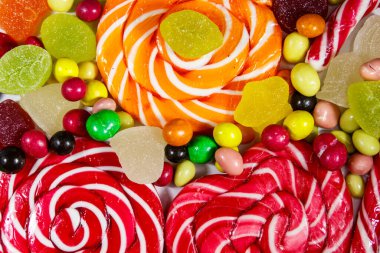 Renkli çikolata şekerleri, lolipoplar, şeker kamışı ve jöleli şekerlerin arka planı