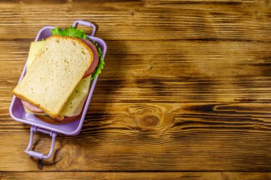 Tahta bir masanın üzerinde sandviçlerle beslenme çantası. Üst görünüm, alanı kopyala