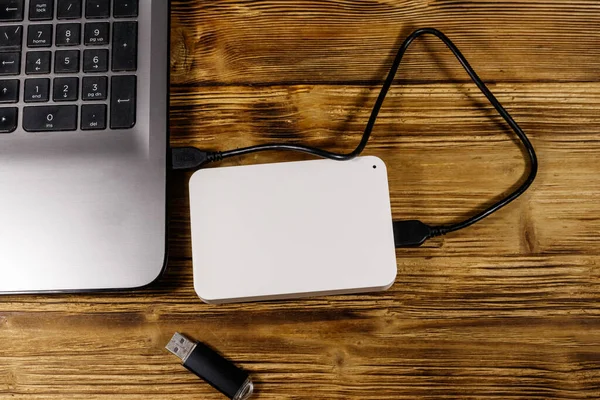 Harici HDD, tahta bir masadaki dizüstü bilgisayara ve USB flash diske bağlı. Üst Manzara. Veri depolama kavramı