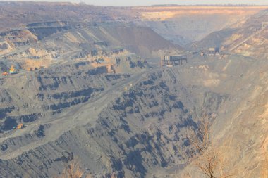 Çalışan çöp kamyonları ve kazıcıları olan dev bir demir cevheri ocağı.