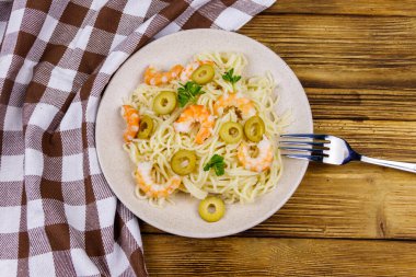 Karidesli spagetti makarna, yeşil zeytin ve ahşap masada maydanoz. Üst görünüm