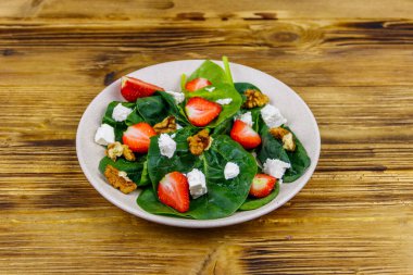Tahta masada çilekli, ıspanaklı, cevizli ve peynirli taze sağlıklı salata.