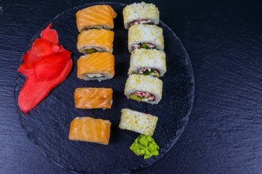 Suşi seti siyah bir taş tahtada yuvarlanıyor. Üst görünüm