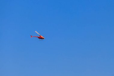 Mavi gökyüzünde uçan turuncu helikopter