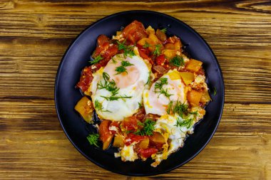 Ev yapımı shakshuka - kızarmış yumurta, soğan, dolmalık biber, domates ve dereotlu ahşap masa. Yahudi mutfağı. Üst görünüm