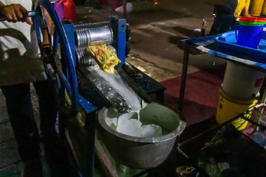 Şeker kamışı sıkma makinesi, Zanzibar, Tanzanya 'daki Stone Town' daki Forodhani bahçe pazarında taze şeker kamışı suyu yapıyor.