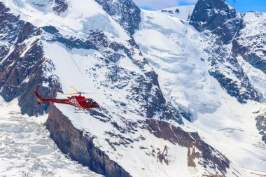 İsviçre 'deki karlı İsviçre Alpleri üzerinde uçan helikopter.