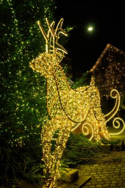 Noel geyikleri gece karanlığında çok renkli ışıklarla süslenmiş Noel ağacının yanında