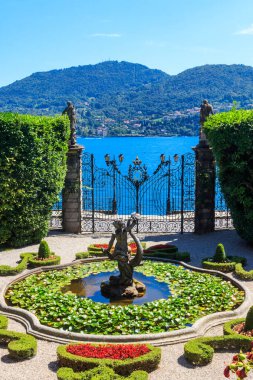 Tremezzo, İtalya - 8 Ağustos 2024: Ünlü Villa Carlotta çeşmesiyle ana kapı ve bahçe ve Tremezzo, İtalya 'daki Como Gölü' nün nefes kesici manzarası