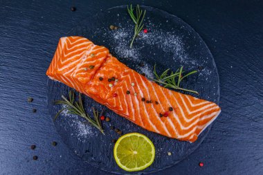 Çiğ somon fileto ve siyah tahta üzerinde baharat. Üst görünüm