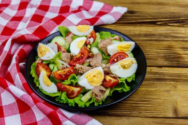 Yumurtalı lezzetli ton balığı salatası, marul ve ahşap masada taze sebze.
