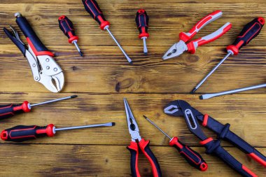 Tahta arka planda farklı pense ve tornavidalar var. Üst görünüm, alanı kopyala