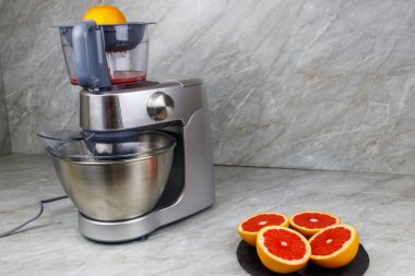 Mutfak masasında modern elektrik sıkacağı ve greyfurt. Taze sıkılmış greyfurt suyu hazırlanıyor.