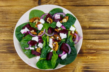 Haşlanmış pancar, peynir, ceviz ve ahşap masada kırmızı soğanlı ıspanak salatası. Üst Manzara. Sağlıklı vejetaryen yemekleri