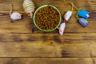 Kedi ve kase için tahta arka planda kuru hayvan mamasıyla fare oyuncakları. Üst görünüm, boşluğu kopyala. Hayvan bakımı konsepti