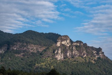 Mavi gökyüzü ve beyaz bulutlar, dağdaki her çeşit taş ve bitki.