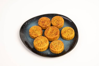 Altın ay kekleri beyaz bir arka planda bir tabağa konur. Ay çörekleri 