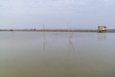 Karanlık sahilde topraktan yapılmış çiftlikler ve yollar var.