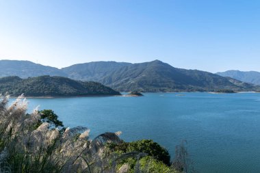 Gölün karşısında dağ, gökyüzü mavi ve göl suyu mavi.