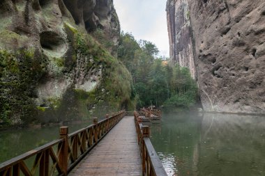Her iki tarafında ağaçlar ve kayalar olan ormanın derinliklerine giden bir yol.