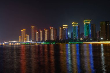 Geceleri şehirde, renkli ışıklar nehrin suyuna yansıyor.