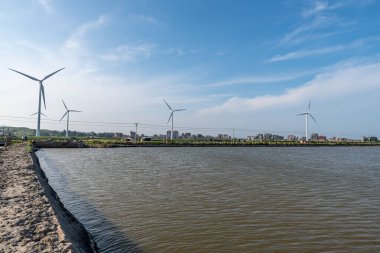 Mavi gökyüzünün altında kıyı şeridi rüzgar türbini