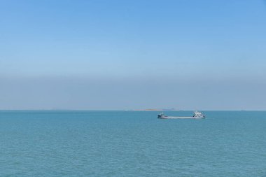 Mavi gökyüzünün altındaki okyanus, limanda ya da denizde kalan gemi.