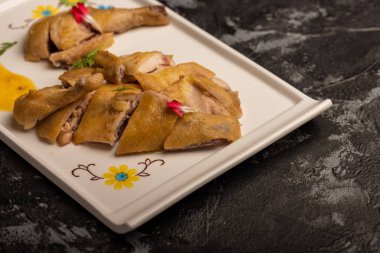 Uzun beyaz tabakta sarı ördek ahşap masada.