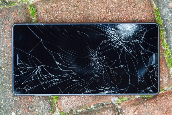 Broken mobile phone lying on pavement — Stock Photo, Image