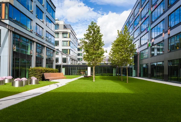 Modern office park with green lawn, trees and bench — Stock Photo, Image