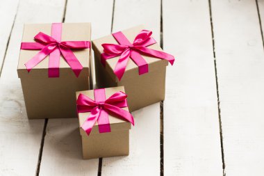 Beyaz ahşap zemin üzerinde pembe kurdele ile Noel hediyeleri