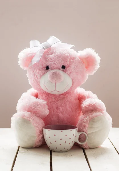 Розовый плюшевый медведь на белом деревянном фоне с чашкой чая — стоковое фото