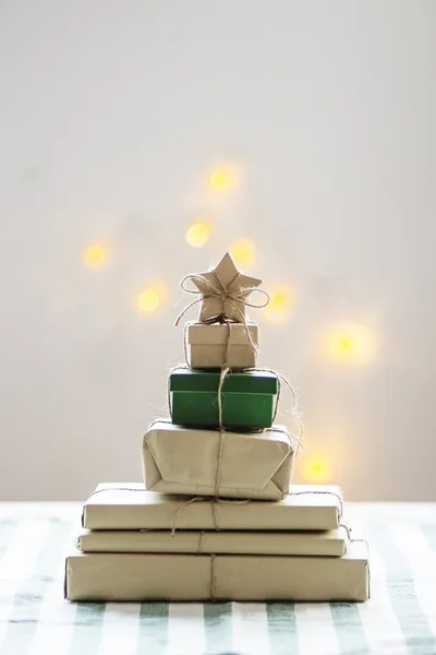 Julgran formade presenterar med stjärna på toppen och lampor i bakgrunden — Stockfoto