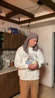 Mutfakta eskrim yapan bir adam, merdaneyi kılıç olarak kullanıyor. Ev ortamında yaratıcı, esprili ve esprili hareketler. Tam vücut çekim, dinamik hareket, eğlenceli ve enerjik sahne