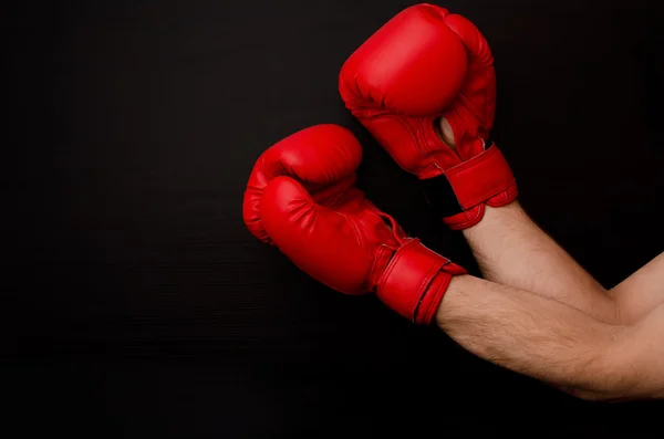 Hand in red boxing gloves in the corner of the frame on a black background, empty space — Stok fotoğraf