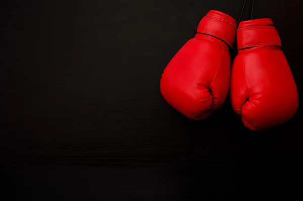 Две красные боксерские перчатки в верхнем углу рамки на черном фоне, пустое пространство — стоковое фото