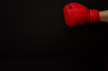 Hand in red boxing gloves on a black background empty space.