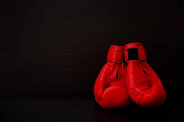 Duas luvas de boxe vermelhas no lado da moldura em um fundo preto, espaço vazio — Fotografia de Stock