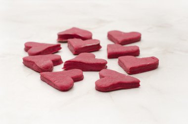 Red heart-shaped cookies on a white table closeup, baking for Valentine's Day
