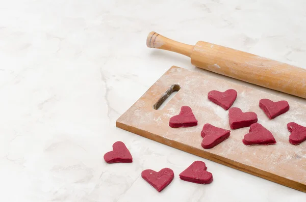 Wooden board with red hearts made of dough on a white table with copy-space.  Valentine's Day. — Stok fotoğraf